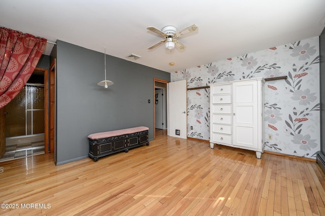 bedroom with light wood finished floors, visible vents, wallpapered walls, baseboards, and a ceiling fan