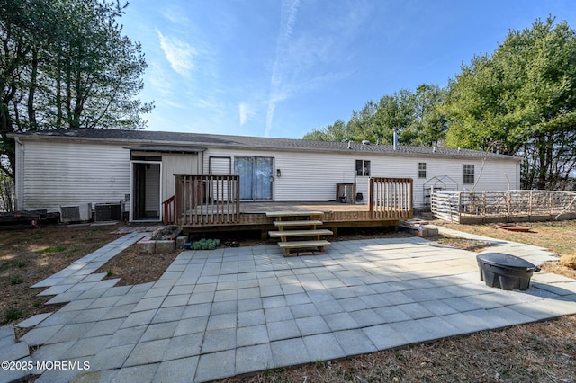 rear view of house with a wooden deck, central air condition unit, a patio area, and a fire pit