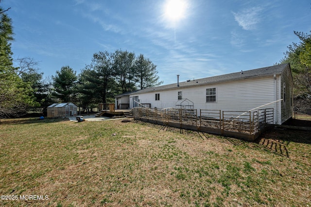 rear view of house with an outbuilding, a deck, an exterior structure, and a yard