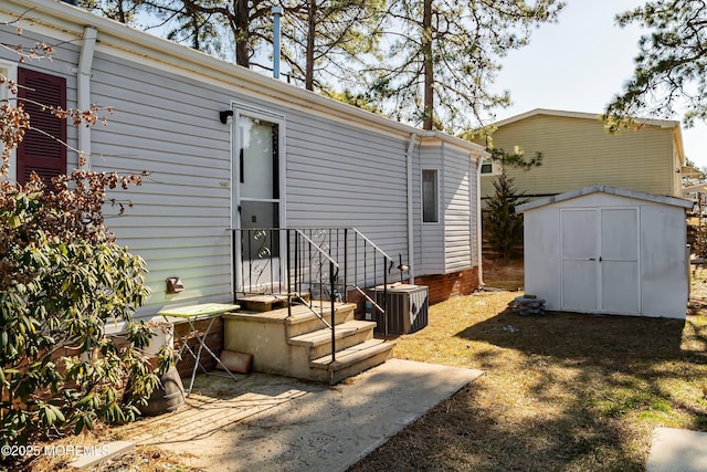 back of house featuring central air condition unit, an outdoor structure, and a shed