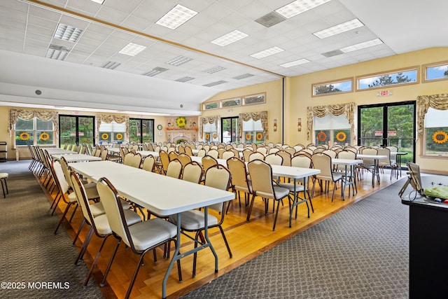 dining area with lofted ceiling, carpet floors, and wood finished floors