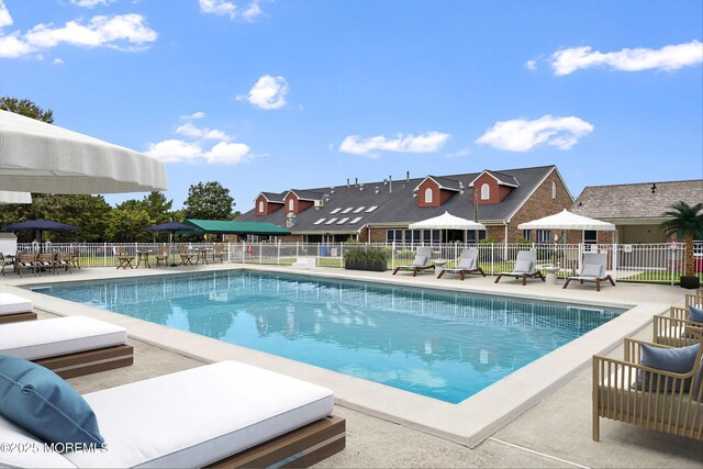 community pool featuring a residential view, a patio, and fence