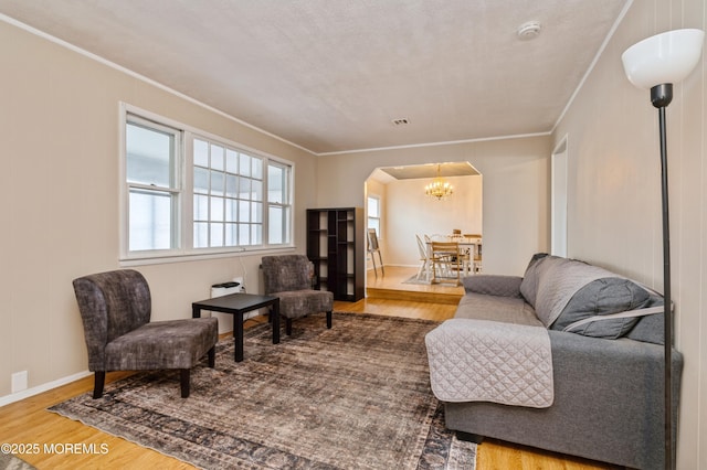 living room featuring visible vents, a chandelier, ornamental molding, wood finished floors, and arched walkways