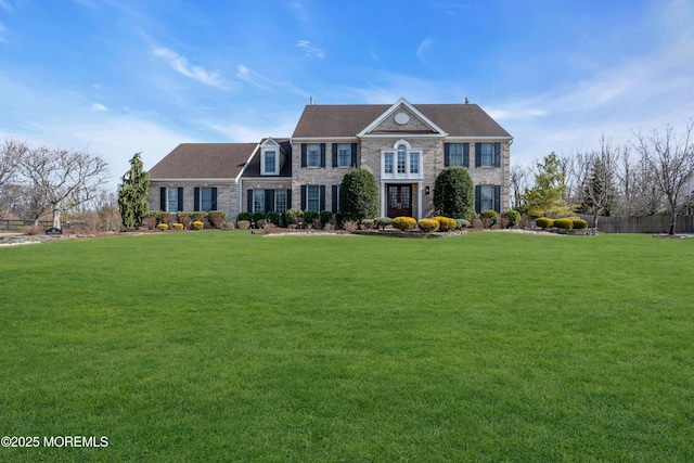 colonial home featuring stone siding and a front lawn