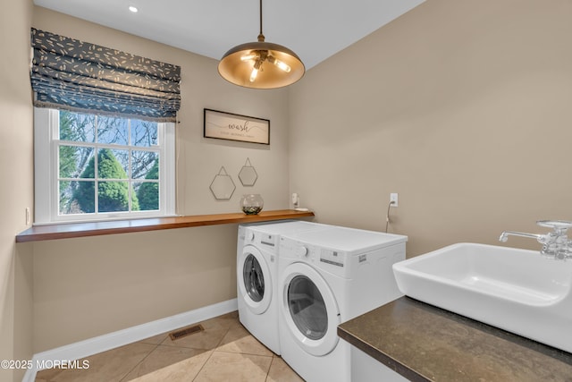 laundry area with independent washer and dryer, a sink, light tile patterned floors, baseboards, and laundry area