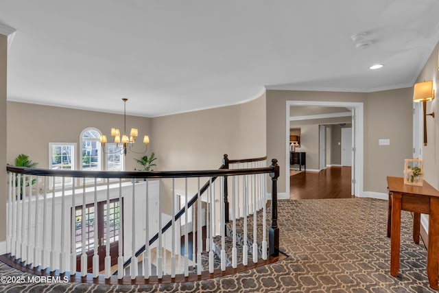 hall featuring baseboards, a chandelier, ornamental molding, an upstairs landing, and carpet floors