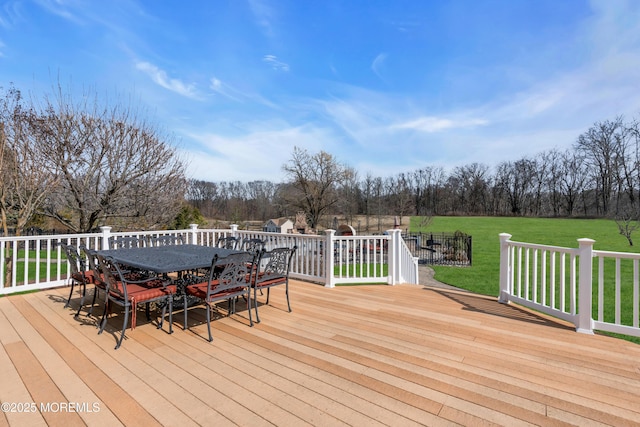 wooden terrace with outdoor dining space and a lawn