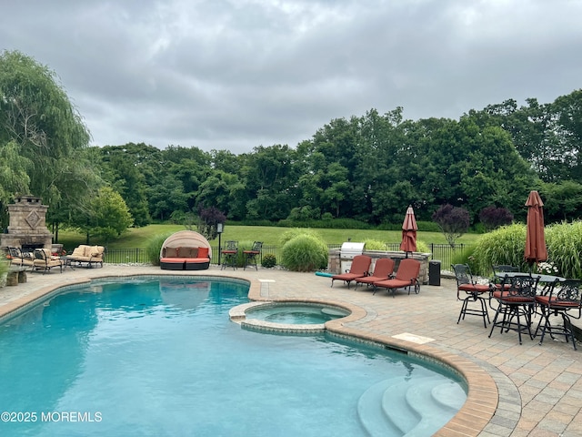 view of pool featuring a patio, fence, a pool with connected hot tub, and an outdoor stone fireplace