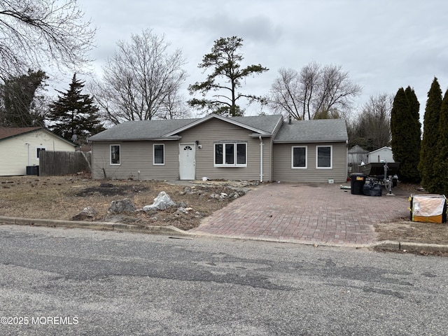 view of front facade with fence, central AC, and a shingled roof