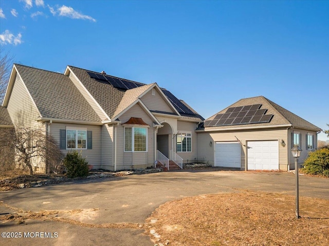 view of front of property featuring roof mounted solar panels, concrete driveway, an attached garage, and a shingled roof