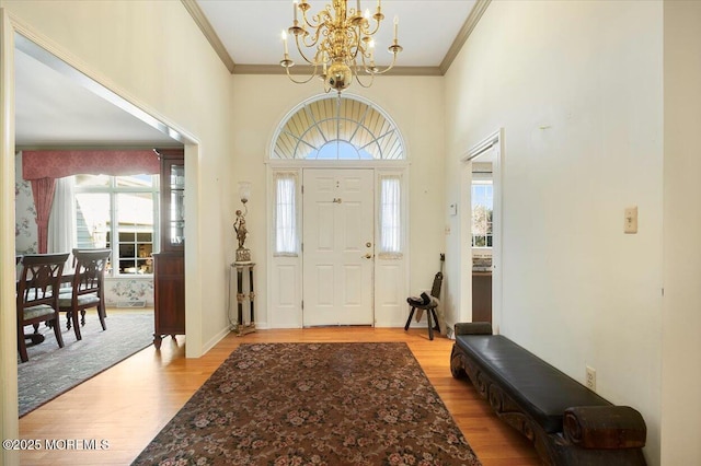 entrance foyer featuring an inviting chandelier, light wood-type flooring, and ornamental molding