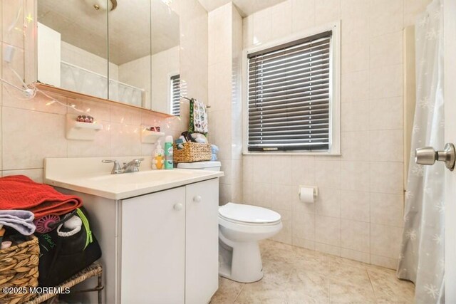 bathroom featuring tile patterned flooring, a shower with curtain, tile walls, toilet, and vanity