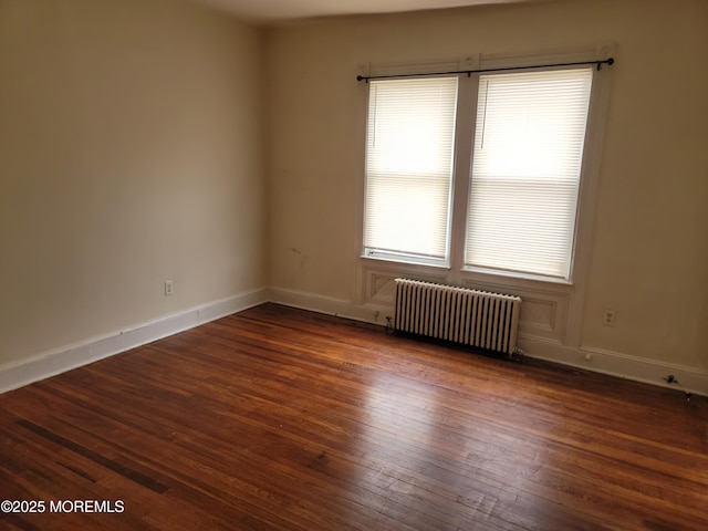 spare room with dark wood finished floors, radiator heating unit, and baseboards