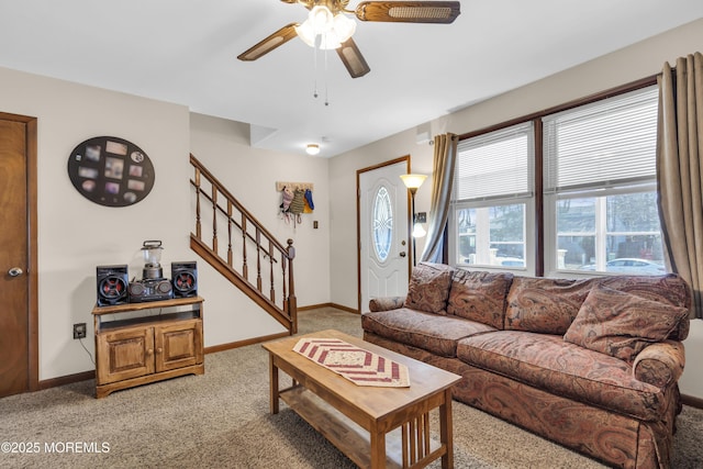 living area featuring stairway, light carpet, baseboards, and ceiling fan