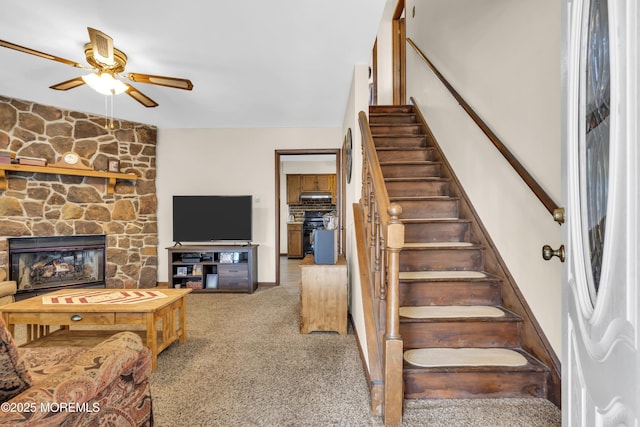 stairway featuring a fireplace, a ceiling fan, and carpet