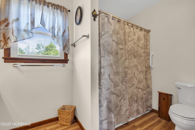 bathroom with curtained shower, baseboards, toilet, and wood finished floors