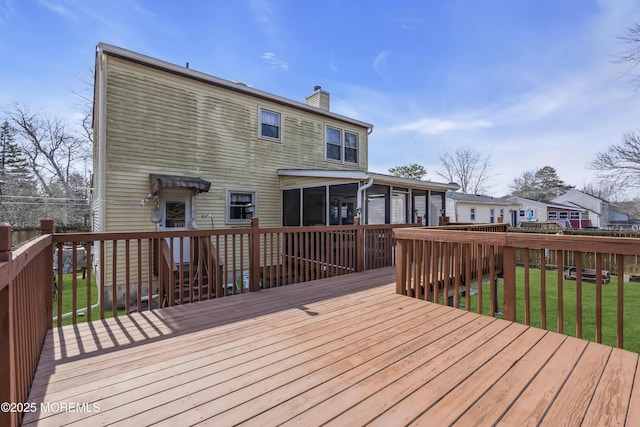 wooden deck with a yard and a sunroom