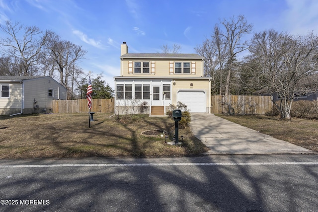 traditional-style house with driveway, a chimney, an attached garage, and fence