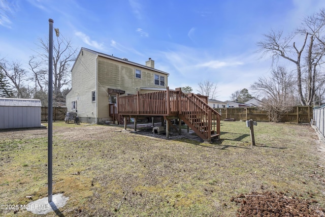 rear view of house with stairway, a fenced backyard, a chimney, and a wooden deck