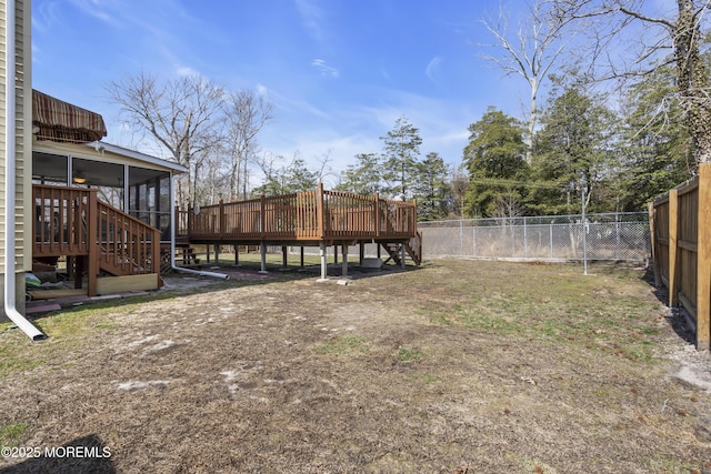 view of yard featuring stairway, a deck, a fenced backyard, and a sunroom