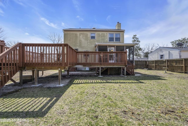 rear view of house with a wooden deck, fence, a lawn, and a chimney