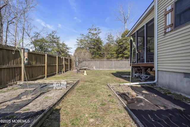 view of yard with a vegetable garden, a fenced backyard, and a sunroom