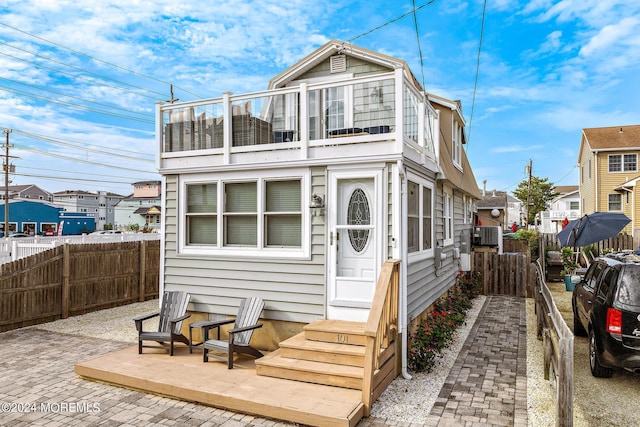 back of property with a patio area, entry steps, a balcony, and fence