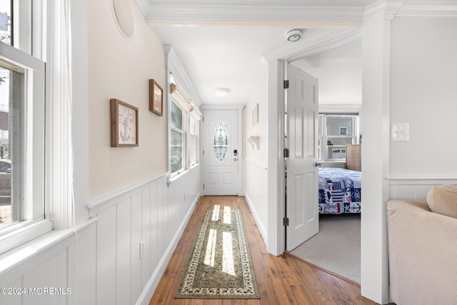 interior space featuring wainscoting, ornamental molding, and wood-type flooring