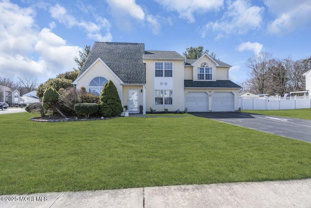 view of front of house featuring a front yard, fence, driveway, roof with shingles, and a garage