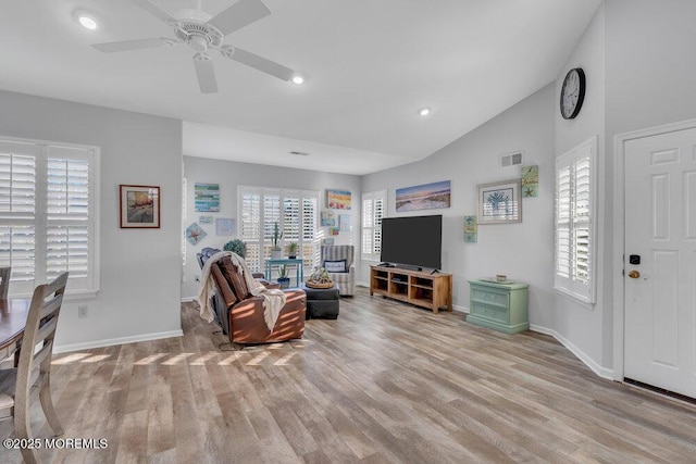 living area featuring a wealth of natural light, wood finished floors, and vaulted ceiling