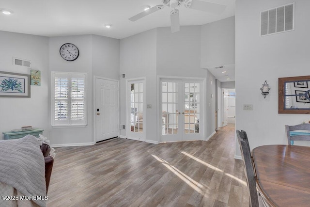 foyer entrance featuring wood finished floors, visible vents, a towering ceiling, and baseboards