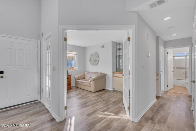 foyer entrance featuring visible vents, baseboards, and light wood-style floors