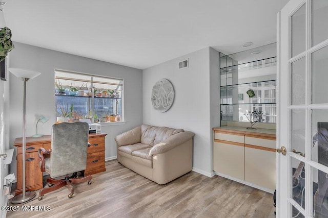 home office featuring light wood-type flooring, visible vents, and baseboards