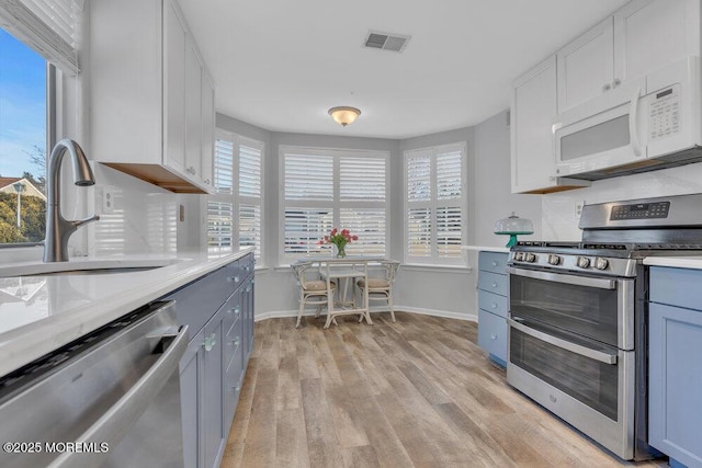 kitchen featuring light wood finished floors, visible vents, light countertops, stainless steel appliances, and a sink