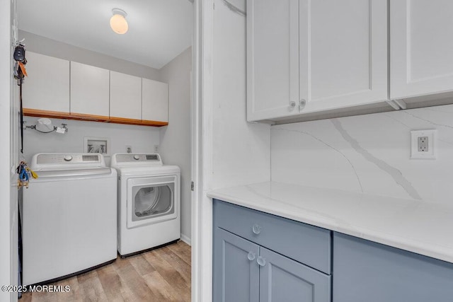 washroom featuring washing machine and clothes dryer, cabinet space, and light wood-style floors