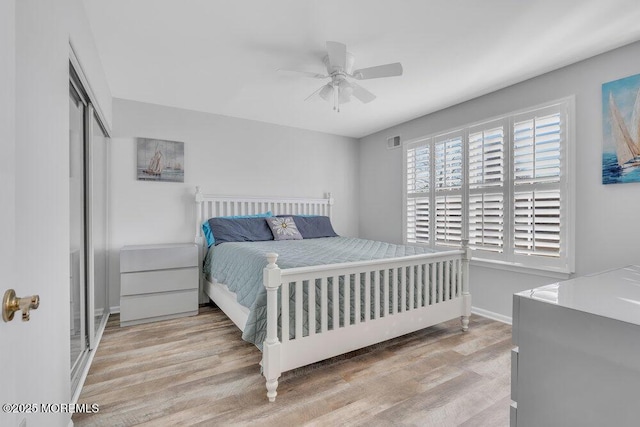 bedroom featuring visible vents, ceiling fan, baseboards, wood finished floors, and a closet