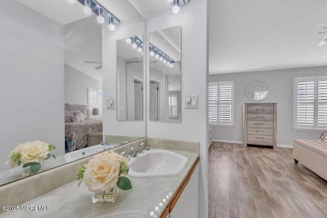 bathroom with wood finished floors, a healthy amount of sunlight, ensuite bath, and a ceiling fan