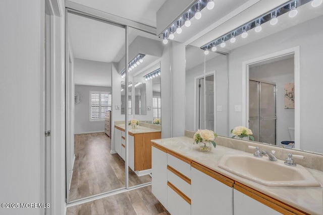 bathroom featuring vanity, toilet, wood finished floors, and a stall shower