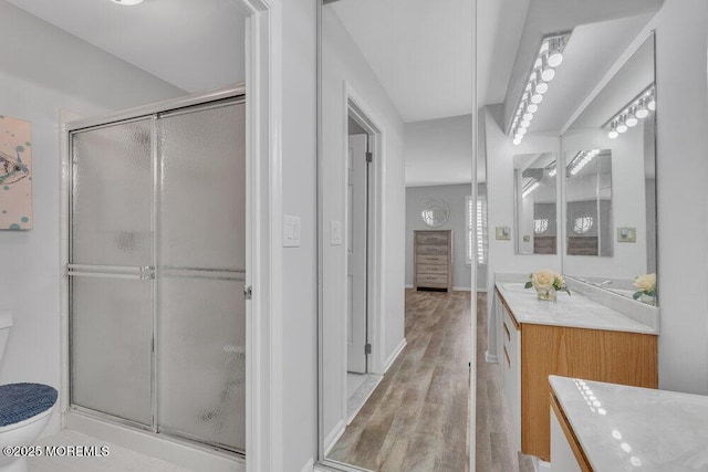 full bath with wood finished floors, toilet, a stall shower, and vanity