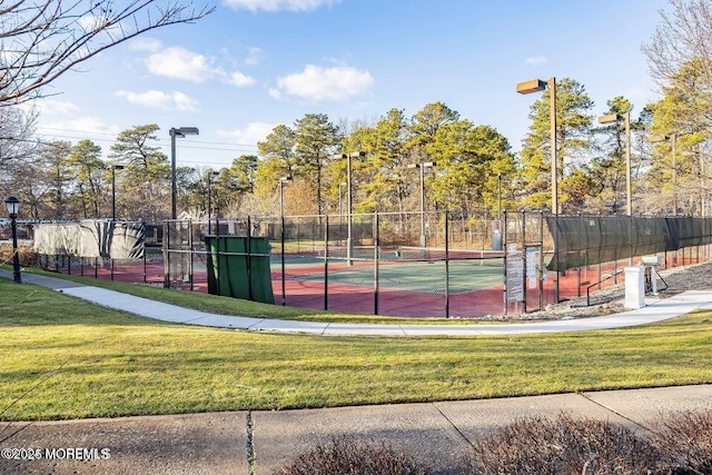 view of tennis court featuring a yard and fence