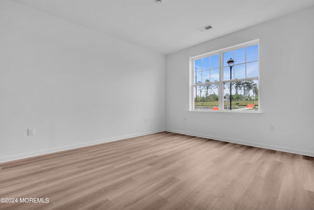 unfurnished room featuring light wood-style flooring, baseboards, and visible vents