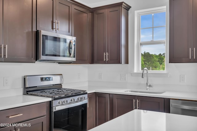 kitchen with dark brown cabinets, appliances with stainless steel finishes, light countertops, and a sink