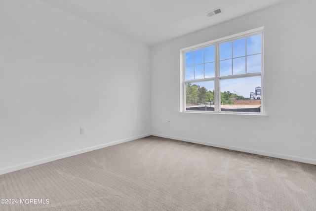 carpeted empty room featuring visible vents and baseboards