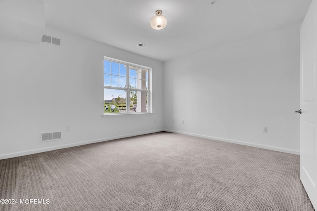 carpeted empty room featuring baseboards and visible vents