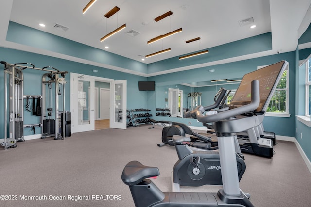 exercise room featuring a raised ceiling, baseboards, and visible vents