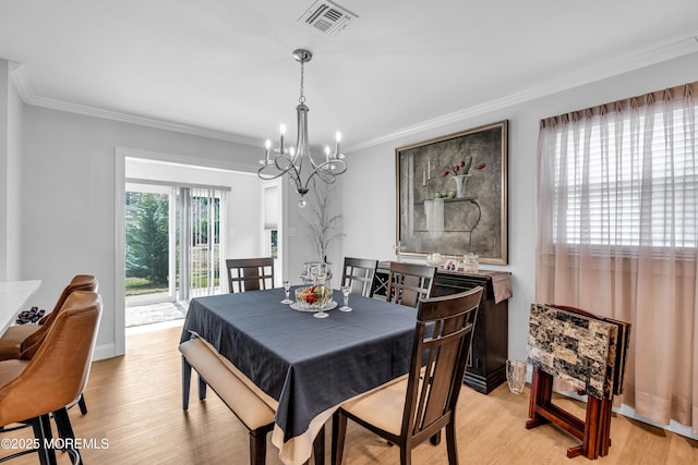 dining area featuring a chandelier, visible vents, light wood-style flooring, and ornamental molding