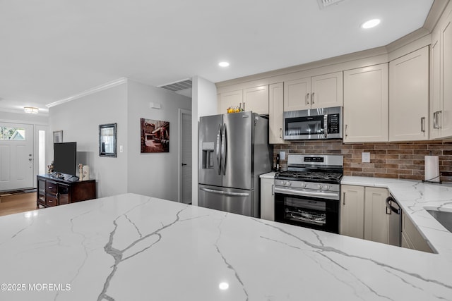 kitchen featuring light stone counters, visible vents, appliances with stainless steel finishes, and decorative backsplash