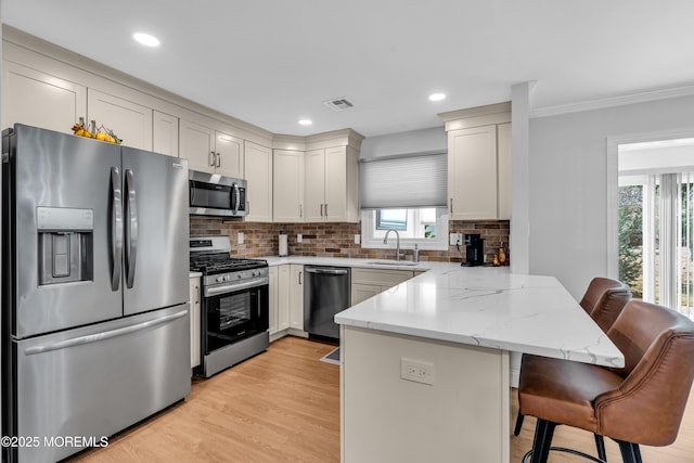 kitchen with visible vents, a peninsula, a sink, stainless steel appliances, and a kitchen bar