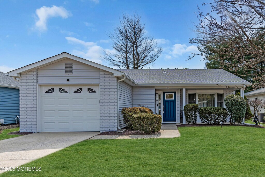 ranch-style home featuring a garage, a front yard, brick siding, and driveway