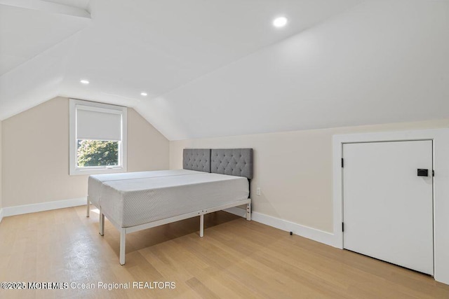 bedroom featuring light wood-type flooring, lofted ceiling, and baseboards